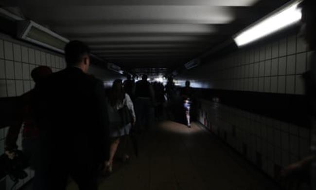 People walking in complete darkness at Clapham Junction station in Lo<em></em>ndon during a power cut.