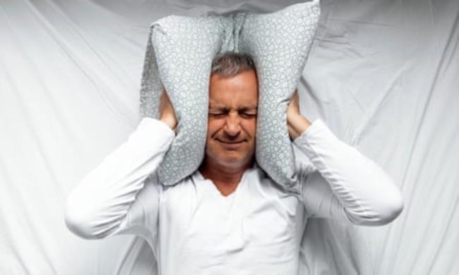 a man presses a pillow to his ears