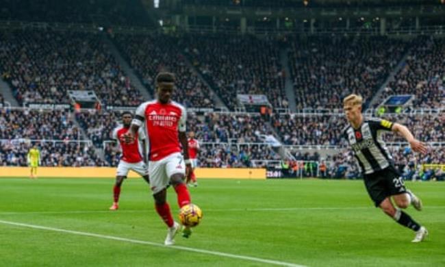 Bukayo Saka dribbles the ball against Lewis Hall during the Premier League match between Newcastle and Arsenal