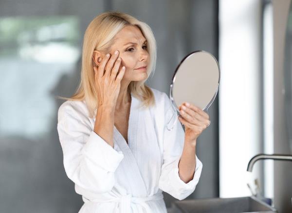 A woman looking critically at herself in the mirror